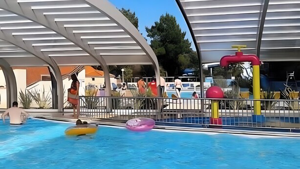 A swimming pool area with a covered deck, a water slide, and inflatable rings. - Lovely mobile home for rent in st jean de monts for an unforgettable vacation (Saint-Jean-de-Monts)
