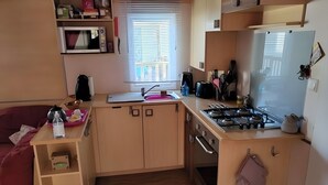 A compact kitchen with a sink, stove, and microwave. - Lovely mobile home for rent in st jean de monts for an unforgettable vacation (Saint-Jean-de-Monts)