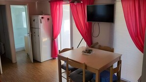 A compact room with a dining table, chairs, a TV, and a refrigerator. - Lovely mobile home for rent in st jean de monts for an unforgettable vacation (Saint-Jean-de-Monts)