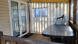 A covered patio with a table and chairs, a sliding glass door, and a view of the house through the window. - Lovely mobile home for rent in st jean de monts for an unforgettable vacation (Saint-Jean-de-Monts)