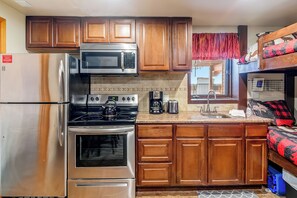 A compact kitchen with wooden cabinets, a stainless steel refrigerator, a microwave, an oven, and a sink. - Hot Tub and Pool access|On Green Run|Free Shuttle (Breckenridge)