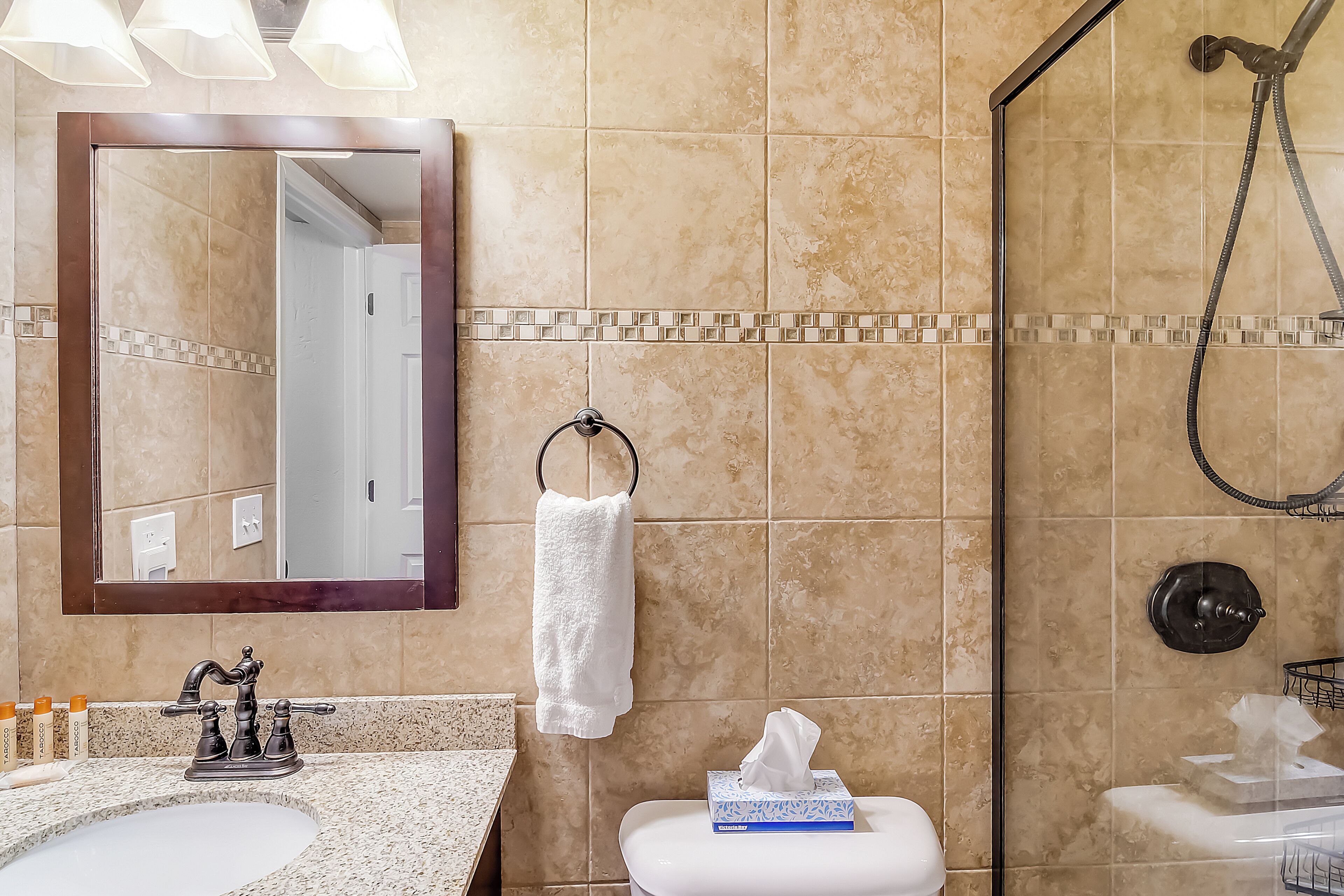 Een badkamer met een wastafel, spiegel, handdoekhouder, toilet en douche.