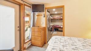 Een slaapkamer met een bed, een dressoir, een televisie en een inloopkast.