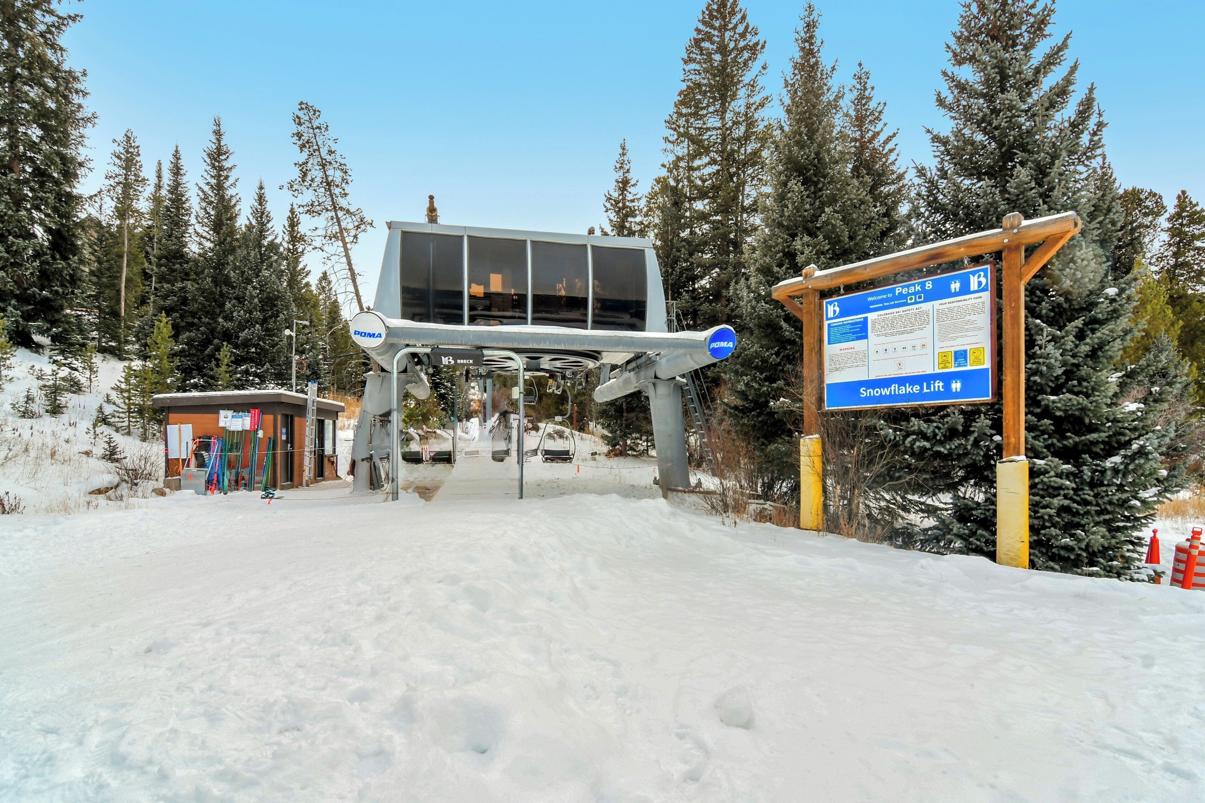 Una stazione di risalita con un cartello che indica 'Snowflake Lift #18' e un edificio con ampie finestre.