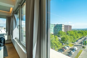 Ein modernes Hotelzimmer mit einem großen Fenster, das einen Blick auf einen Parkplatz und Gebäude bietet.