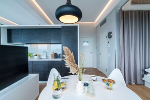 Eine moderne Küche mit dunklen Schränken, einer weißen Arbeitsplatte und einem Essbereich mit einem Tisch, gedeckt für das Frühstück.