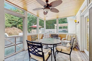 Eine überdachte Terrasse mit Deckenventilator, einem runden Tisch und Stühlen.