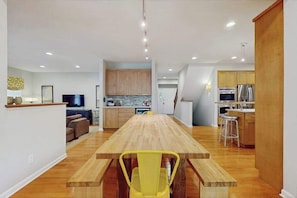 Eine moderne Küche mit Holzschränken, einer zentralen Kochinsel und einem Essbereich mit Holztisch und gelben Stühlen.