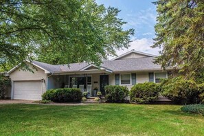 A single-story house with a garage, front porch, and a well-maintained lawn. - Quiet downtown home with hot tub, firepit, washer/dryer - walk everywhere (New Buffalo)