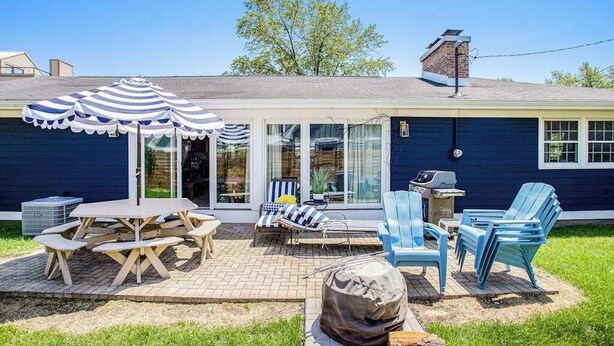 Un jardin avec une table de pique-nique, des chaises longues et un barbecue.