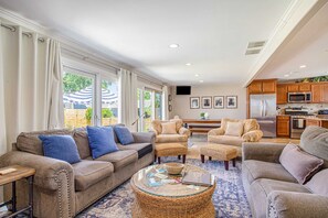 A spacious living room with a large window, a kitchen with modern appliances, and a comfortable seating area. - Remodeled Home close to Lake Michigan - Walk to the Beach, One Dog OK (New Buffalo)
