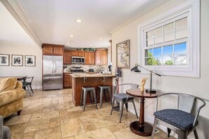 A kitchen with a central island, stainless steel appliances, and a dining area with a table and chairs. - Remodeled Home close to Lake Michigan - Walk to the Beach, One Dog OK (New Buffalo)