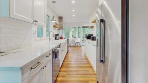 A modern kitchen with white cabinets, stainless steel appliances, and a wooden floor. - Cute Cottage by the Lake W/ Private Hot Tub, Firepit, Screened Porch & Fast WiFi (Michiana)