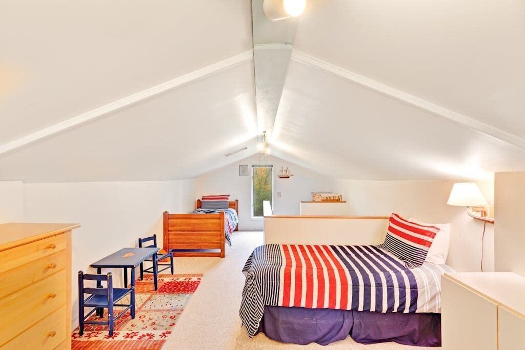 Une chambre à coucher comprenant un lit, un bureau, une chaise, une commode et une fenêtre.