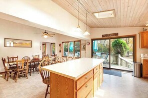 A spacious kitchen with wooden cabinets, a large island, and a dining area with chairs. - Spacious home under a mile to Douglas Beach Great for families or groups (Douglas)