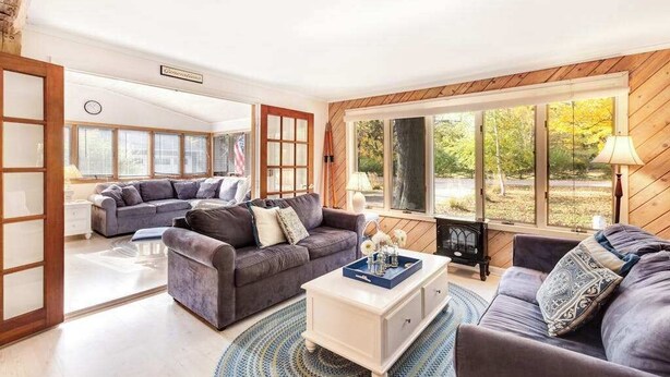 Ein geräumiges Wohnzimmer mit großem Fenster, Kamin und einer gemütlichen Sitzecke.