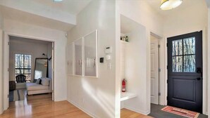 A modern interior with a wooden floor, a black door, and a white wall with a shelf.
