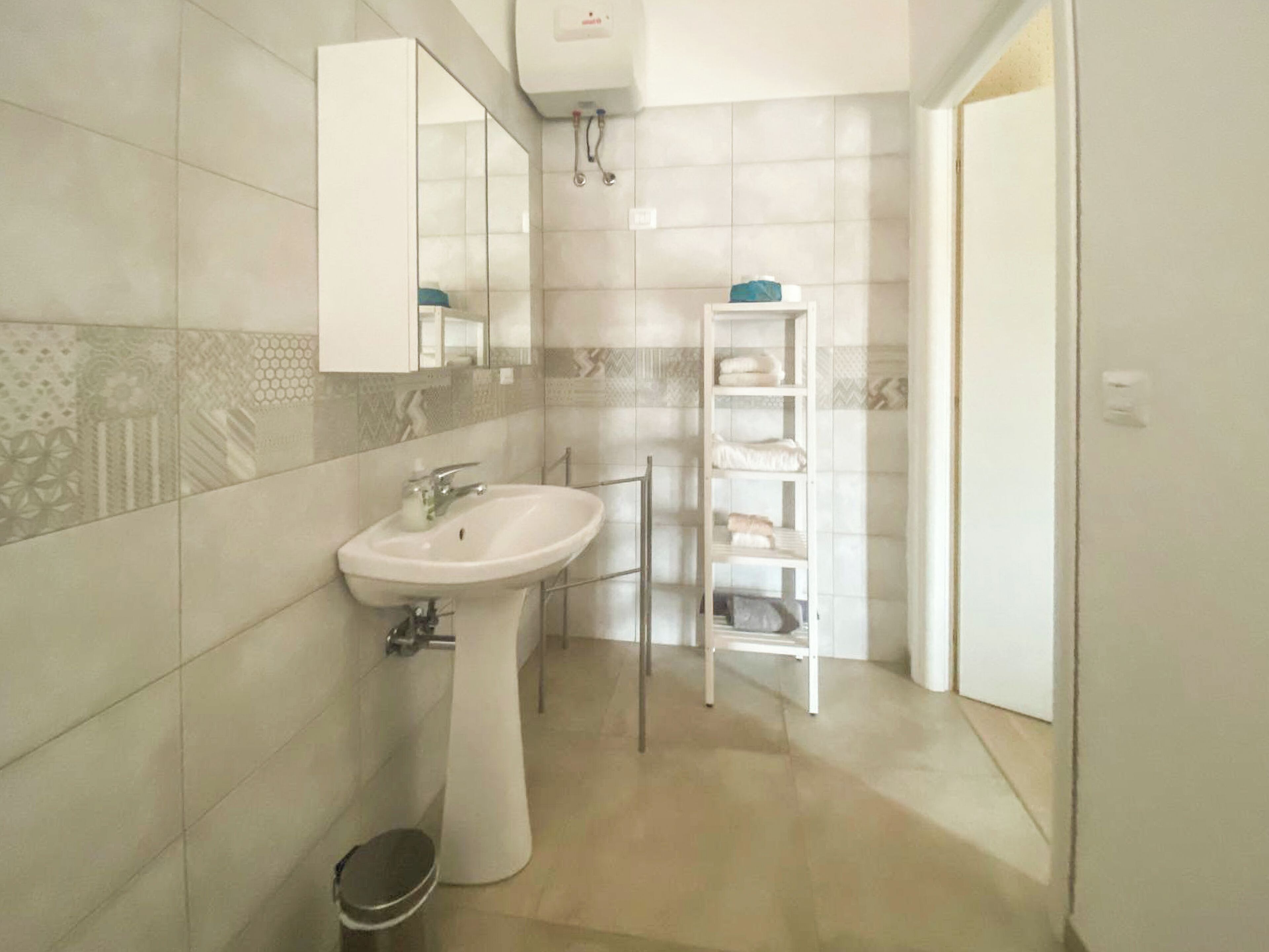 A bathroom with a white sink, a mirror, a towel rack, and a toilet.