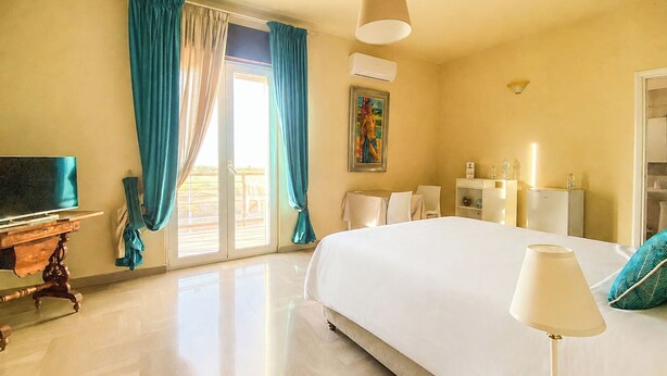 Una habitación de hotel con una cama grande, televisión, escritorio y una silla.