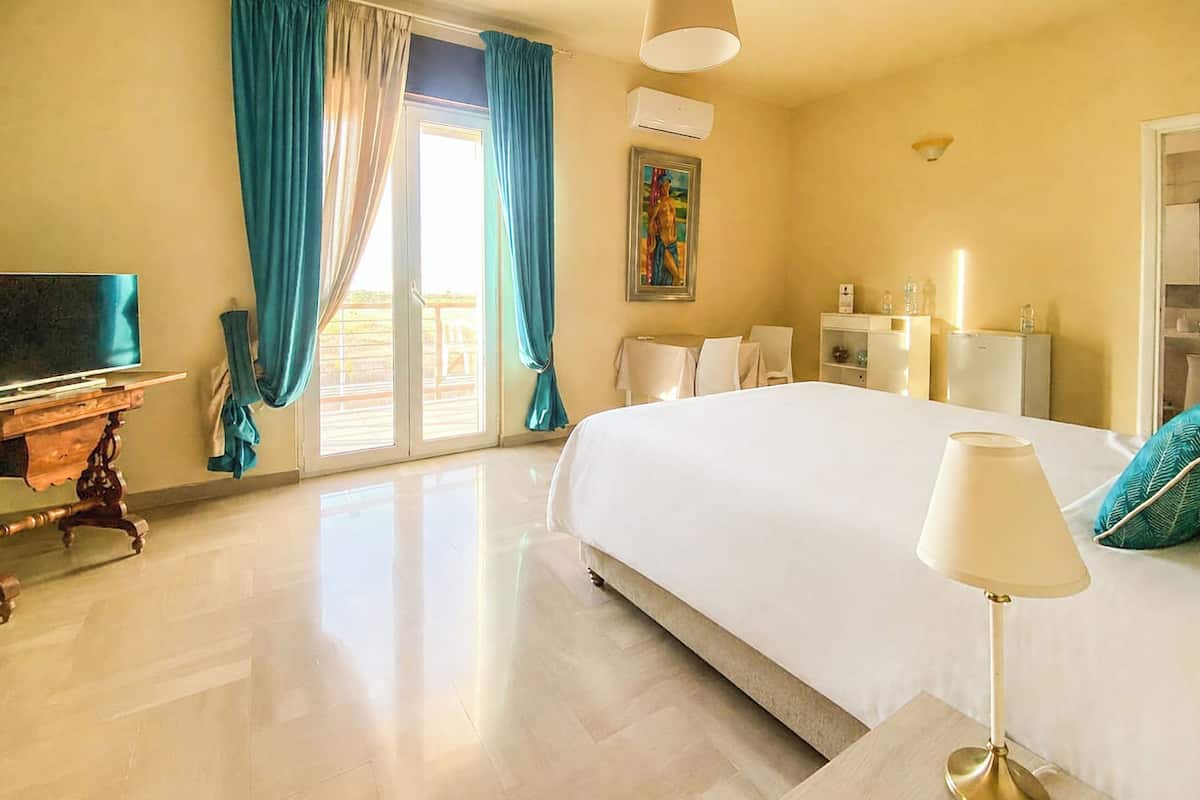 A hotel room with a large bed, a television, a desk, and a chair.