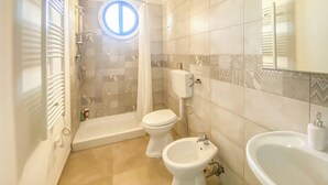 Un baño con ducha, inodoro, bidé y lavamanos.