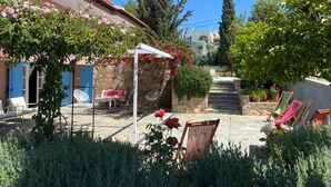A courtyard with a stone pathway, outdoor seating, and a pergola covered with flowering vines. - Villa-Agave, by the sea in Porto-Rafti outside ATH (Porto Rafti)