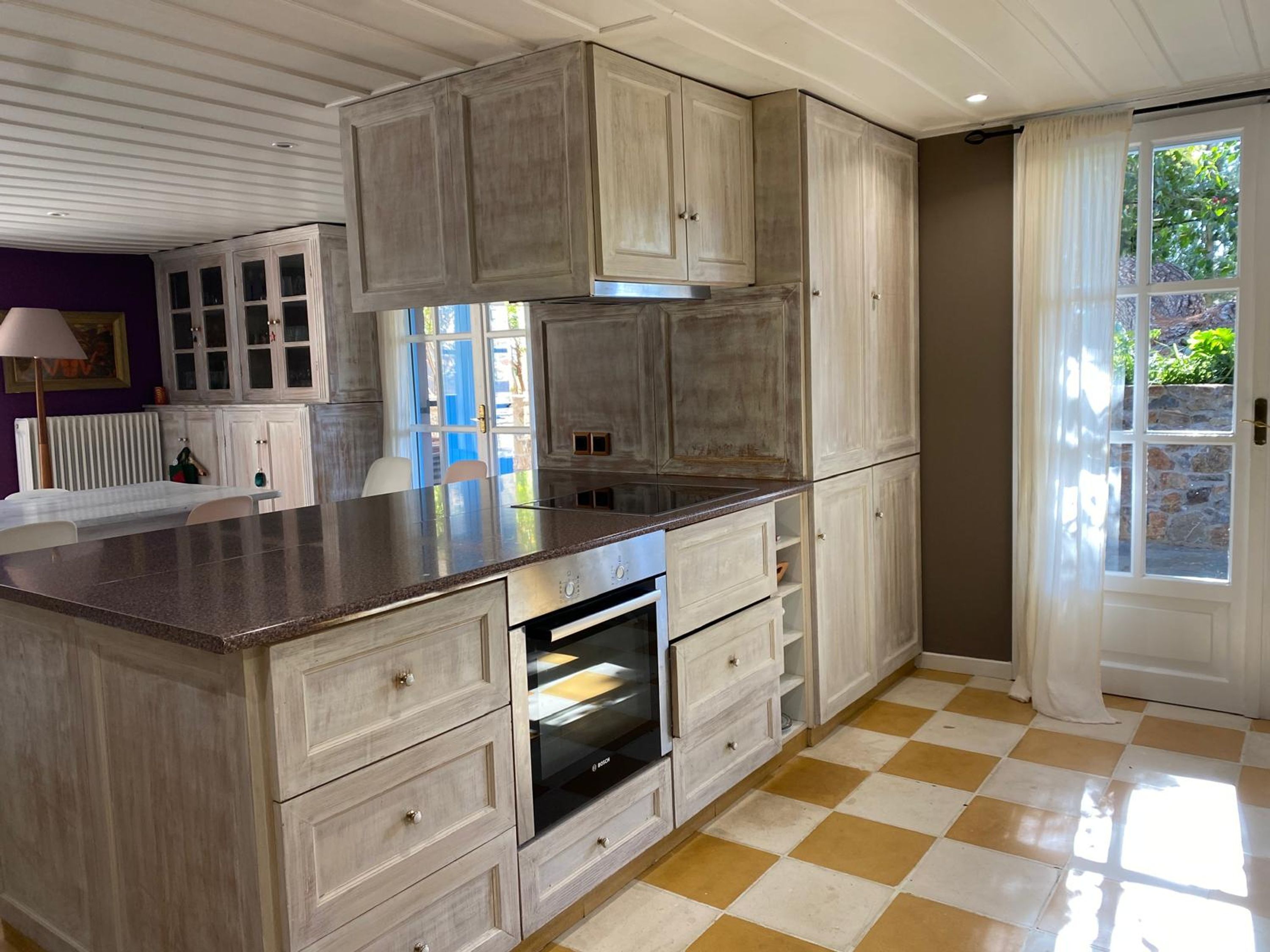 A kitchen with a large island, built-in cabinets, and a checkered floor.