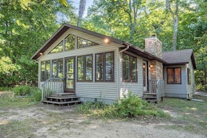 A cabin with a porch, large windows, and a stone chimney. - Private Cottage w/Wood-Burning Fireplace, WiFi, and Lakefront Access (Fennville)