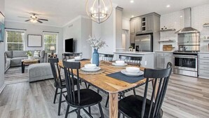 Une cuisine moderne avec un coin repas, un ventilateur de plafond et un four encastré.