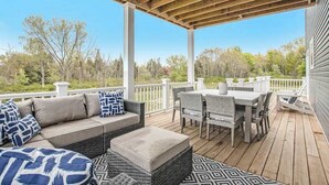 Une terrasse extérieure couverte, aménagée avec un canapé, une table à manger et des chaises.