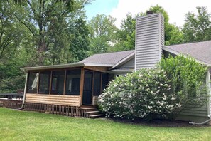 A house with a covered porch, a chimney, and a well-maintained lawn. - Well-kept home with private outdoor pool, free WiFi, and pool table (Sawyer)