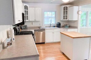 A kitchen with white cabinets, a wooden countertop, a dishwasher, and a window. - Well-kept home with private outdoor pool, free WiFi, and pool table (Sawyer)