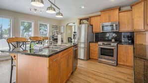 Una cocina moderna con armarios de madera, electrodomésticos de acero inoxidable y una isla central.