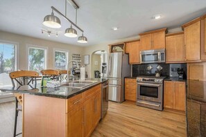 A modern kitchen with wooden cabinets, stainless steel appliances, and a central island. - Fantastic Retreat Near the Lake w/ a Spacious Deck, Firepit, & Private Hot Tub (Saugatuck)