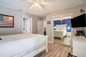 A bedroom with a bed, a ceiling fan, a television, and a door leading to another room. - Fantastic Retreat Near the Lake w/ a Spacious Deck, Firepit, & Private Hot Tub (Saugatuck)