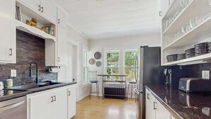 Una cocina moderna con armarios blancos, encimera negra y vistas al exterior a través de amplios ventanales.
