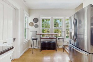 A kitchen with a large stainless steel refrigerator, a radiator, and two bar stools. - Charming historical home with gated entrance & gas grill - walk around downtown (Saugatuck)
