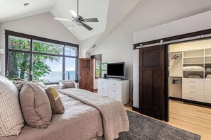A bedroom with a large bed, a television, a wardrobe, and a sliding door leading to a closet. - Lakefront Home w/High-Speed WiFi, Private Beach, Gas Grill, Washer/Dryer, & more (Harbert)