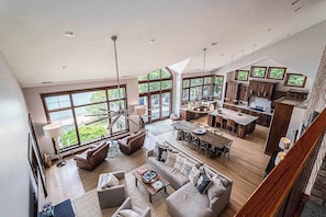 A spacious living area with a large dining table, multiple seating options, and a kitchen area. - Lakefront Home w/High-Speed WiFi, Private Beach, Gas Grill, Washer/Dryer, & more (Harbert)