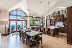 A spacious kitchen with a large island, wooden cabinets, and a view of the outdoors. - Lakefront Home w/High-Speed WiFi, Private Beach, Gas Grill, Washer/Dryer, & more (Harbert)