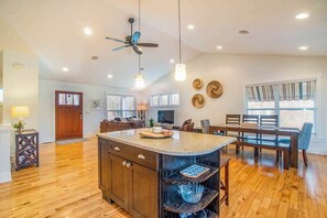 A spacious kitchen with a central island, wooden flooring, pendant lighting, a ceiling fan, and a dining area with a table and chairs. - Dog-friendly home with woodland surroundings- next to Clearbrook Golf Course (Saugatuck)