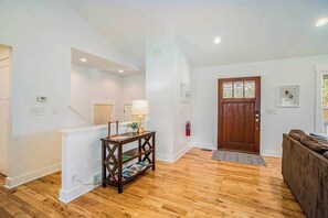 A spacious living area with a wooden floor, a dark wooden console table, a brown door, and a brown sofa. - Dog-friendly home with woodland surroundings- next to Clearbrook Golf Course (Saugatuck)