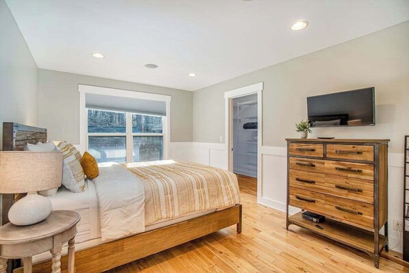 A bedroom with a bed, dresser, TV, and a window with a view. - Beautiful home with woodland surroundings- next to Clearbrook Golf Course (Saugatuck)