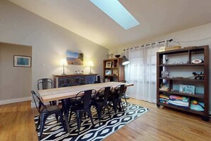 A dining area with a wooden table, black chairs, a patterned rug, a bookshelf, and a ceiling skylight. - Within walking distance to Lake Michigan, beach access, nice patio, W/D & WIFI (Lakeside)