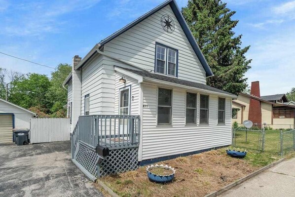 A single-story house with a front porch, a satellite dish, and a fenced yard. - Updated, charming home with huge yard, fire pit, & WiFi - walkable location (South Haven)