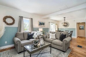 A living room with two sofas, a coffee table, and a chandelier. - Updated, charming home with huge yard, fire pit, & WiFi - walkable location (South Haven)