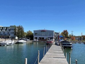 A marina with docked boats, a large building with a red sign, and a clear blue sky. - Historic cozy cottage in Walloon Lake village close to Boyne Mountain skiing! (Walloon Lake)