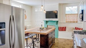 A kitchen with a refrigerator, stove, and bar stools. - Historical dog-friendly home with fenced yard, grill, Ping-Pong, fireplace, & AC (Manistee)