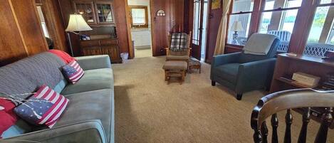A cozy living room with a sofa, armchairs, and a wooden floor.