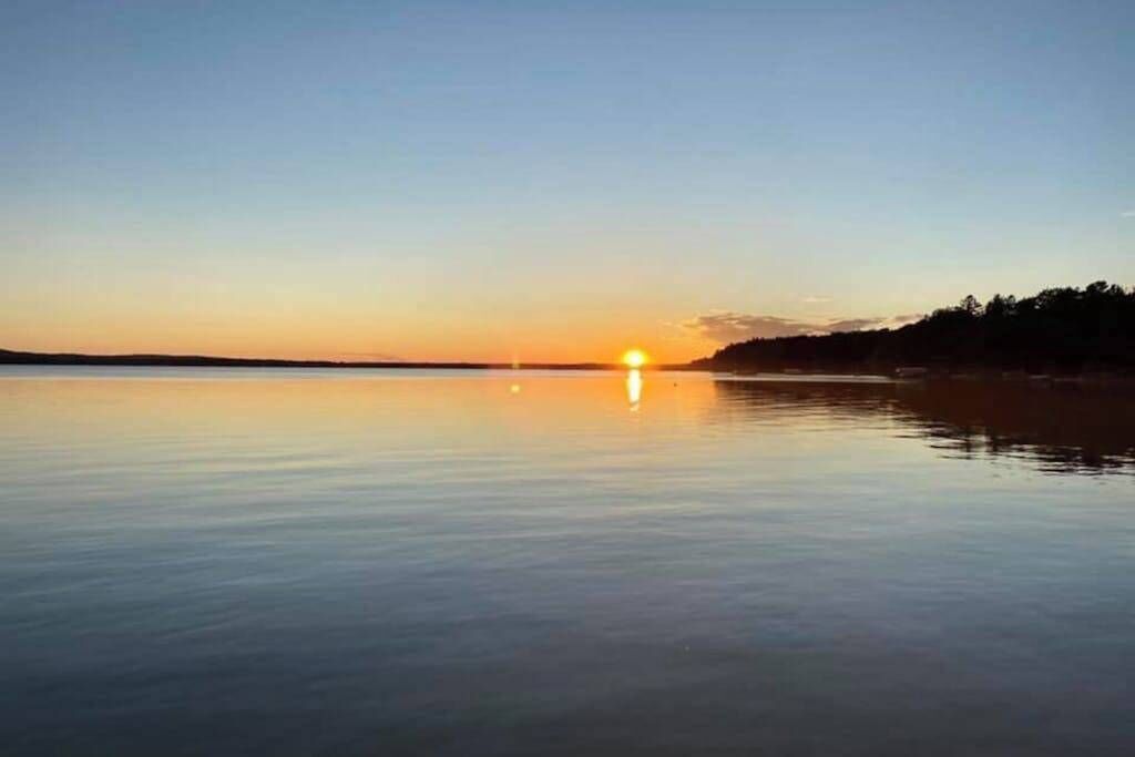 Ruhige Wasserfläche mit untergehender Sonne im Hintergrund.